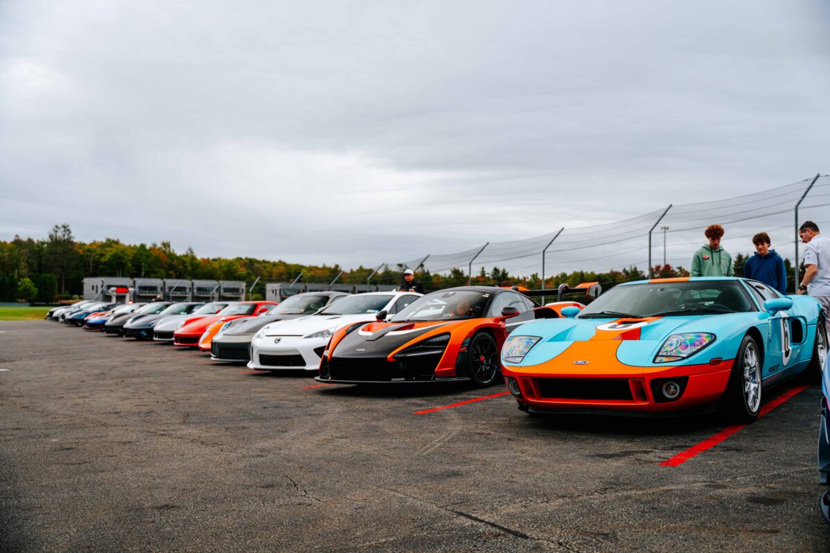 a line of exotic cars along pit lane. Ford GT, McLaren Senna, Lexus LFA, Porsche 911 GT2RS, Porsche 906 and more off in the distance